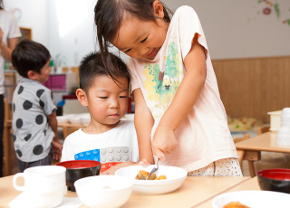 年上の子どもが年下の子どもを手伝う様子